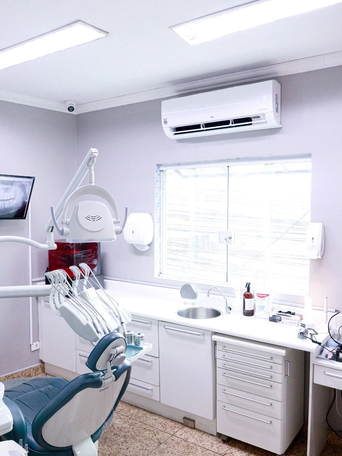 Consultório iluminado com cadeira odontológica e janela